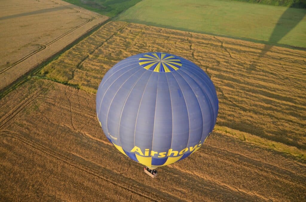 Une montgolfière survolant un champ verdoyant, offrant une perspective unique et sereine du paysage en dessous